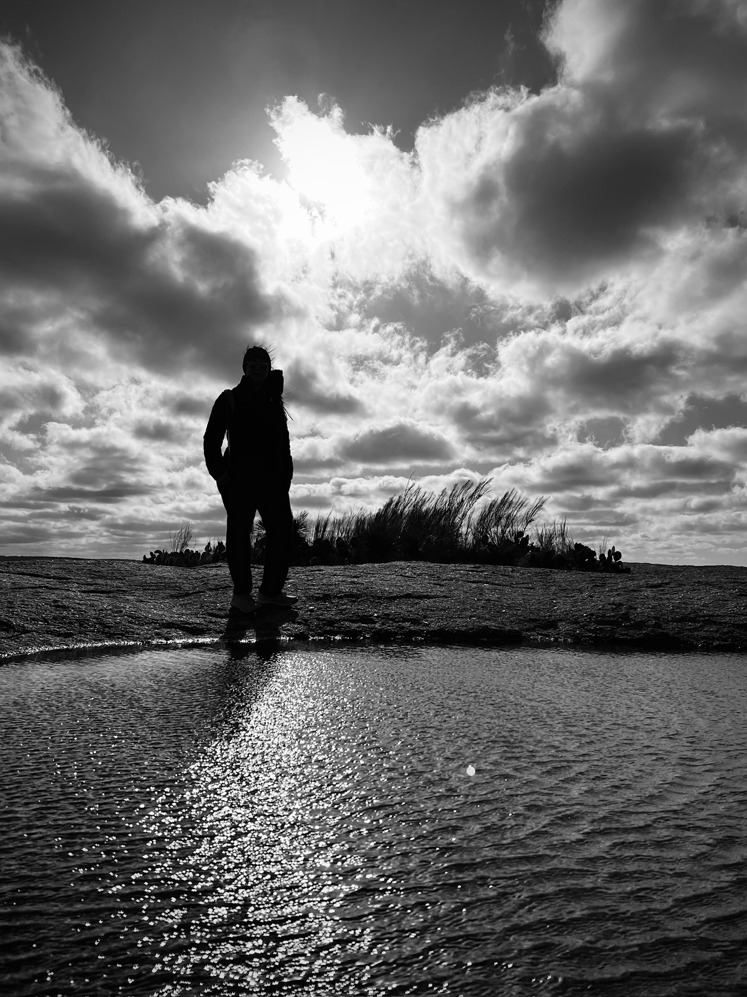 Irma in silhouette between shadow and light at the water's edge